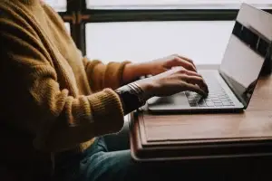 En person som sitter och skriver om tillgänglighet på en laptop.